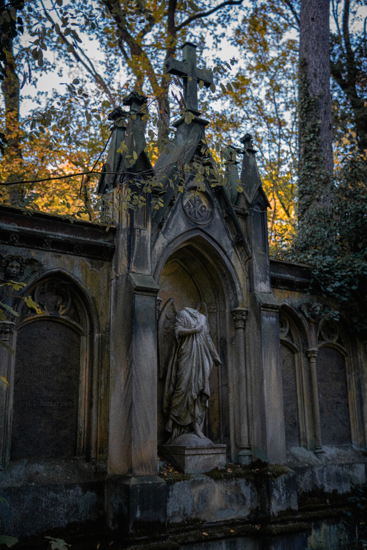 Gothic mausoleum with angel statue and autumn foliage