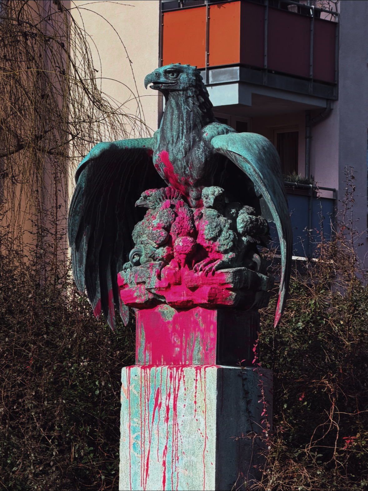 Paint-splashed eagle sculpture in an urban courtyard