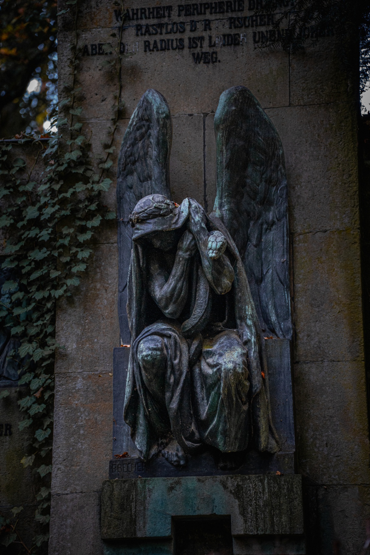 Mourning bronze angel against stone wall