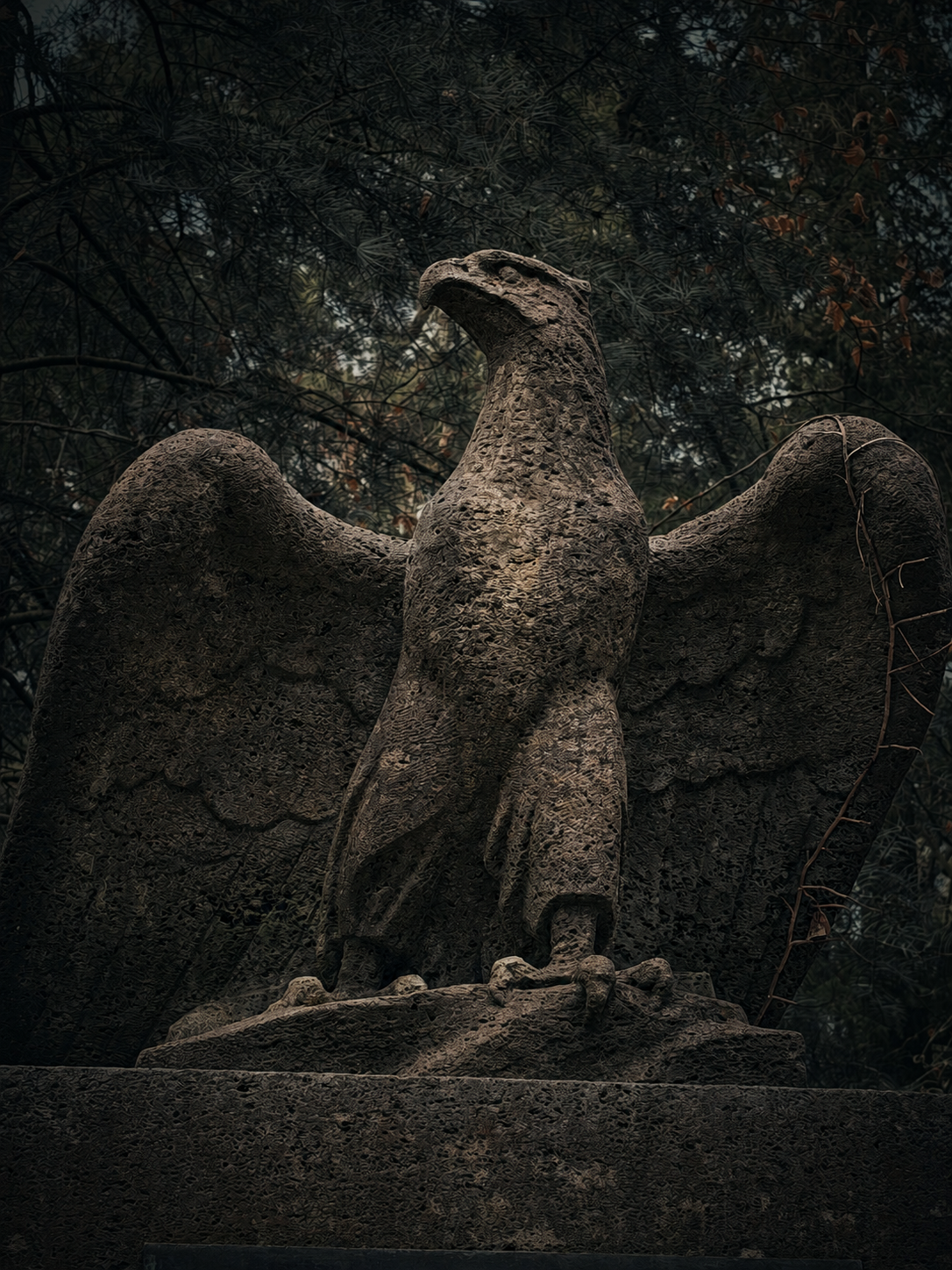 Weathered stone eagle in a wooded setting