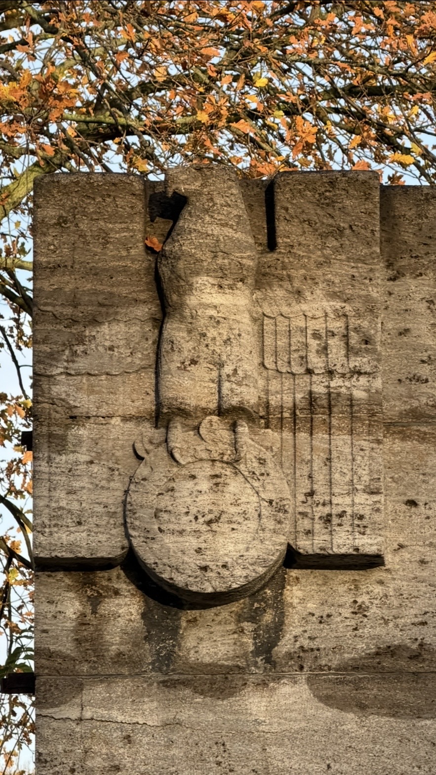 Carved eagle on a concrete monument with autumn leaves