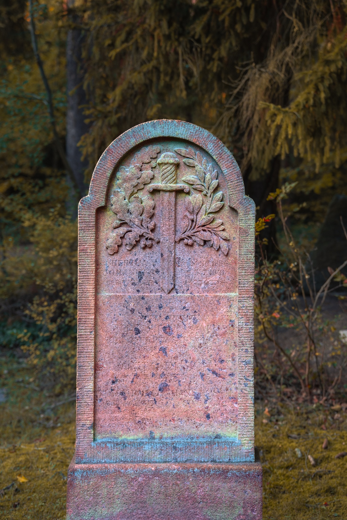 Weathered red sandstone gravestone with sword and wreath